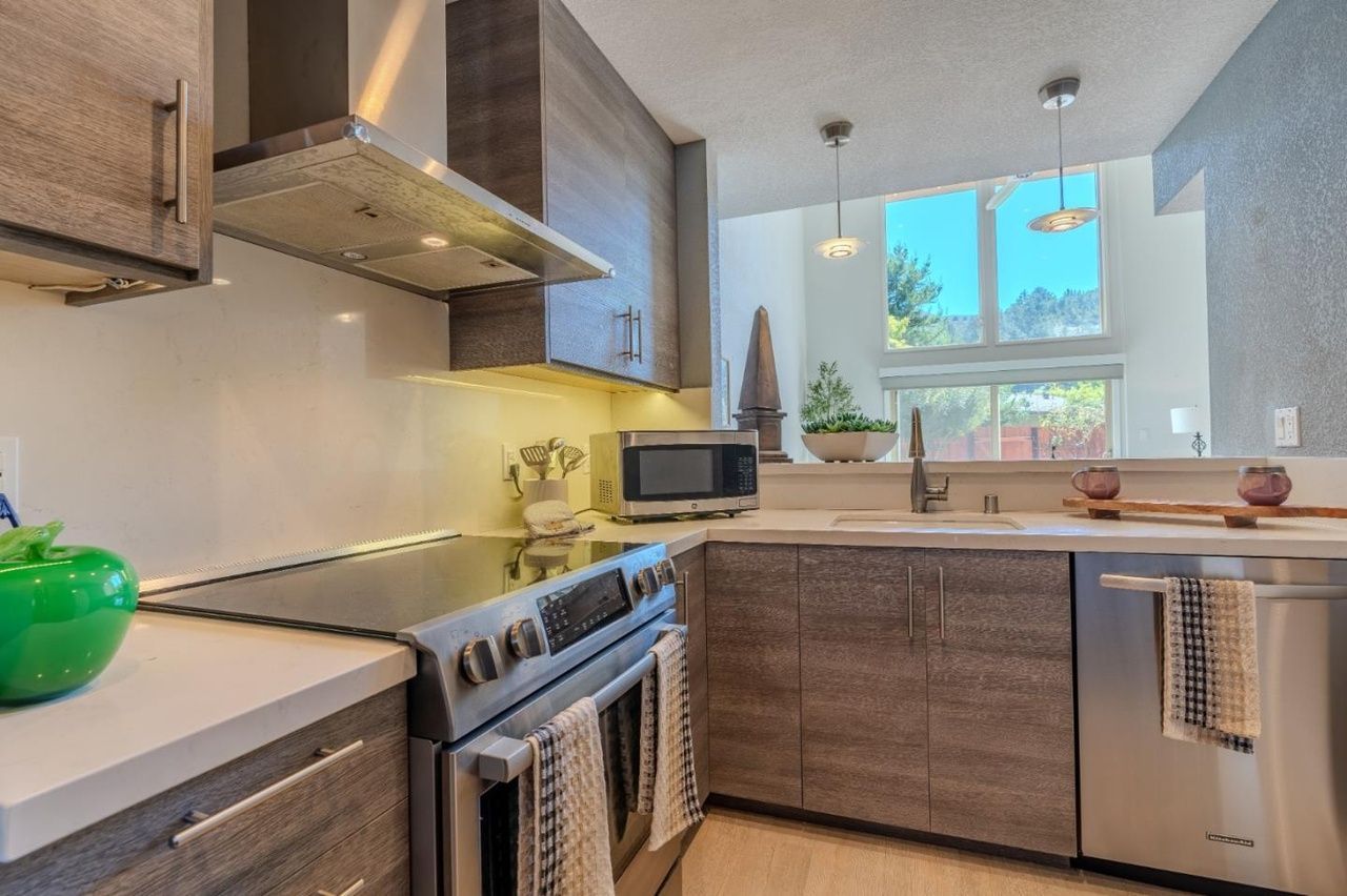 Modern kitchen with stainless steel stove, wood cabinets, and a window over the sink