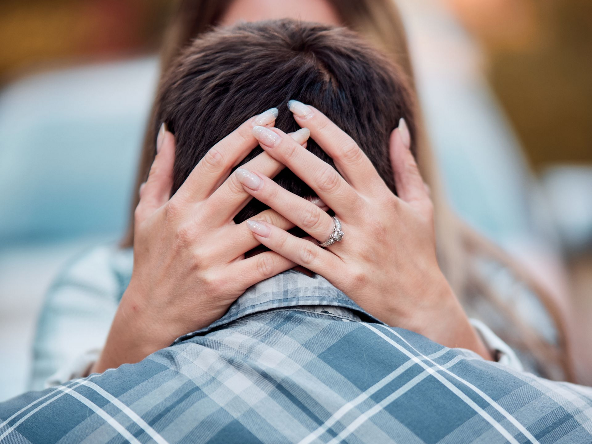 Woman's hands gently cradle a person's head, possibly offering comfort. A diamond ring is visible.