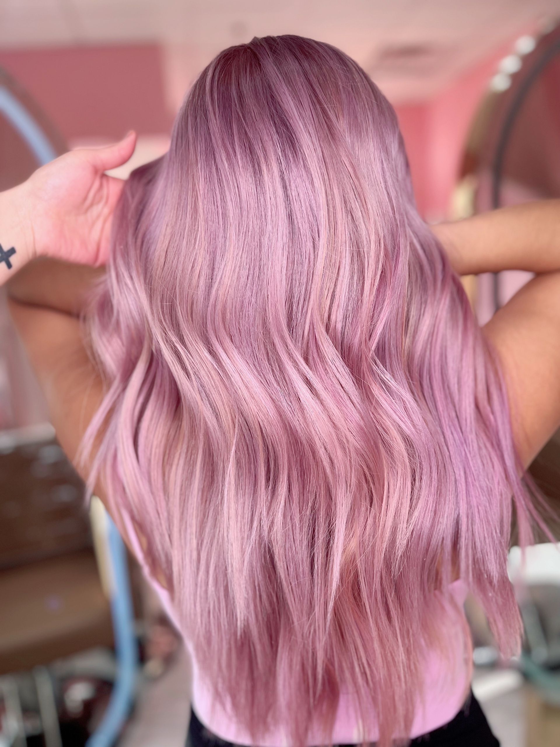 Long hair dyed a dusty rose pink, styled with a mix of crimped and loose wavy textures.