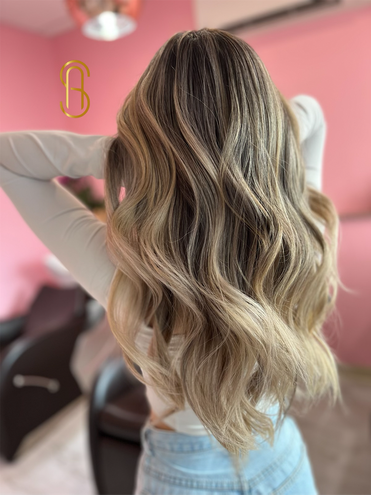Long, wavy hair with blonde highlights styled in a salon, viewed from behind.