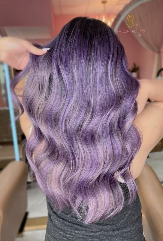 Long, wavy hair dyed in various shades of purple, ranging from deep violet at the roots to soft lavender at the tips.