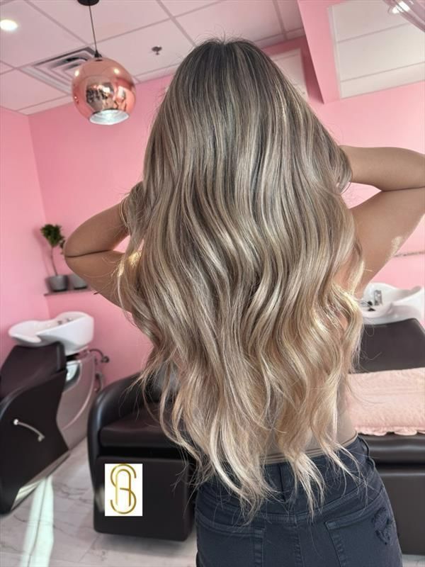 Long, wavy blonde hair with highlights in a pink hair salon.