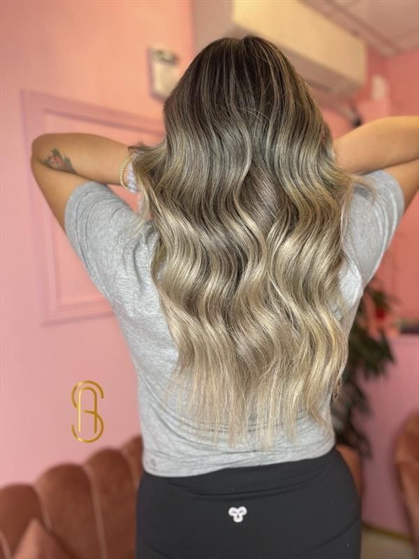 Long, wavy hair with balayage highlights, transitioning from a dark brown root to blonde, viewed from behind.