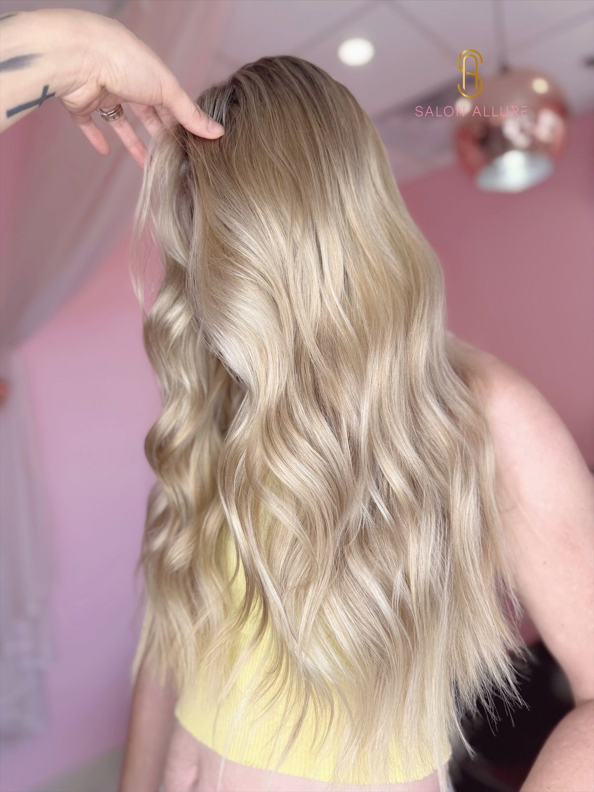 A stylist uses a curling iron on blonde hair in a salon setting.