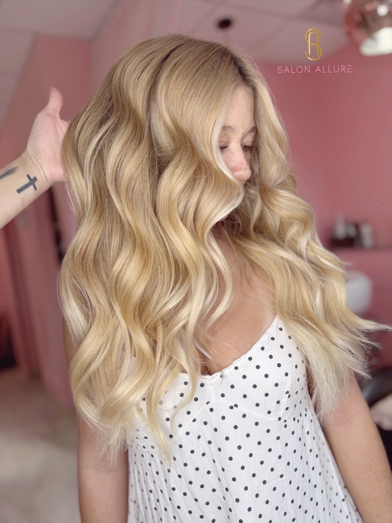 A hairstylist using a comb and fingers to section and prepare blonde hair for a haircut in a salon.