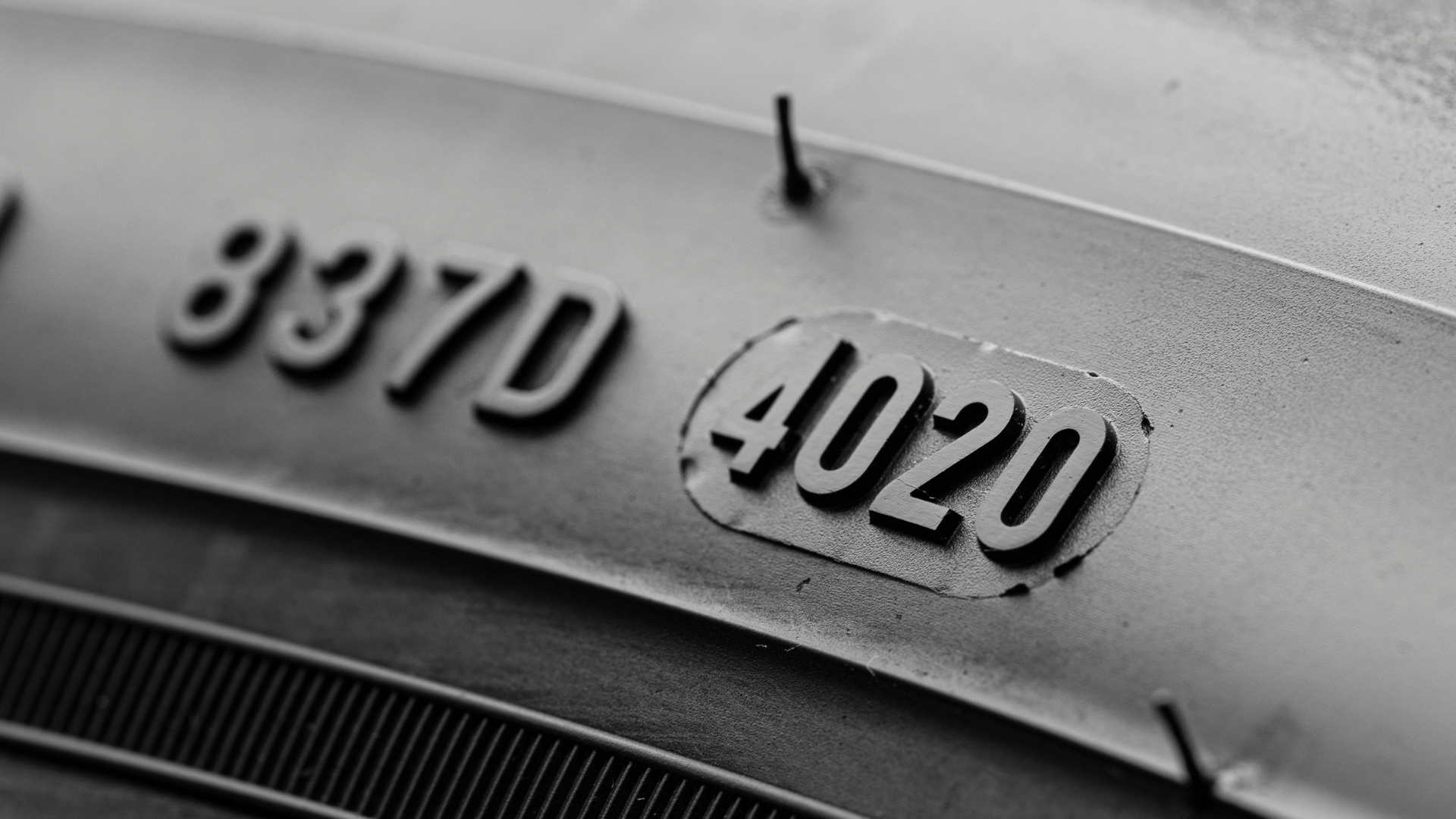 Close-up of a black metal surface stamped with raised numbers “8370” and “402U”
