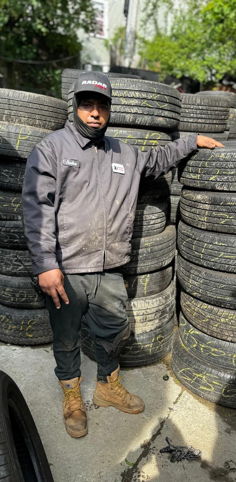 A man is standing in front of a pile of tires.