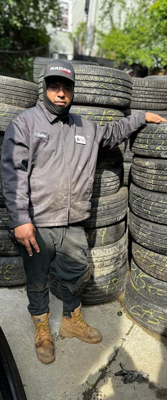 A man is standing in front of a pile of tires.