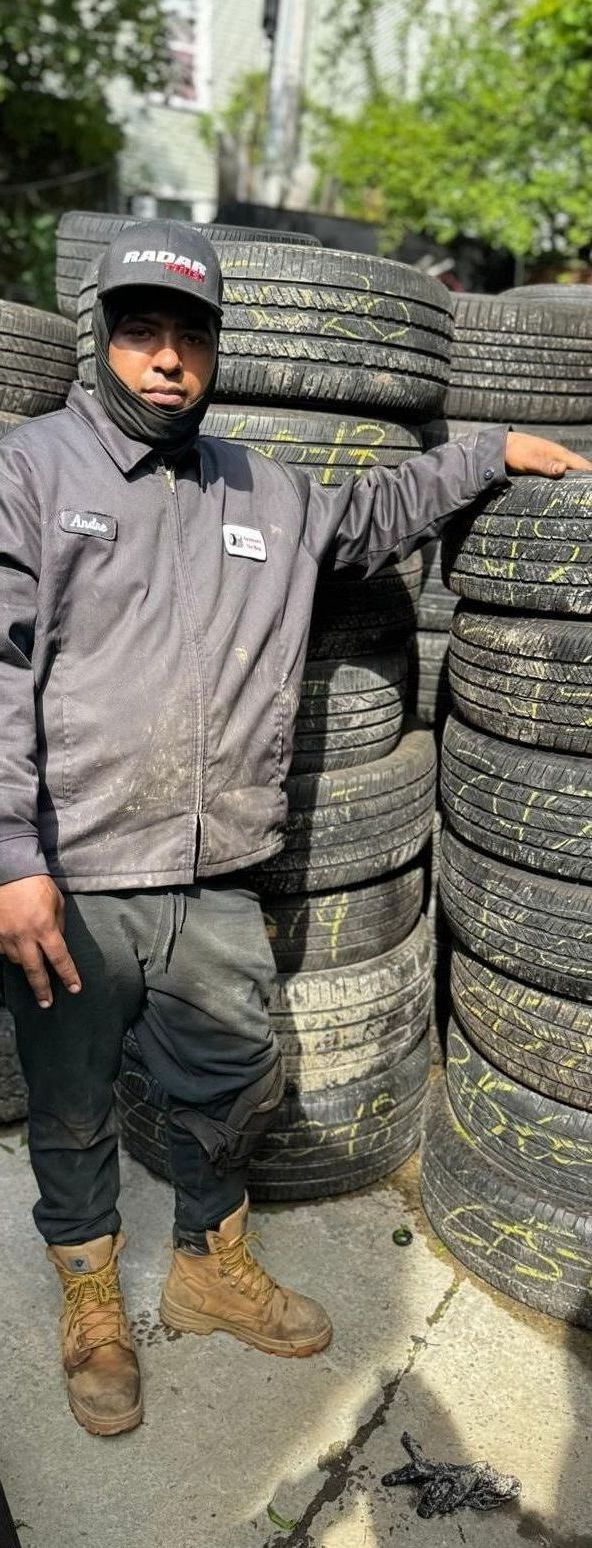 A man is standing in front of a pile of tires.