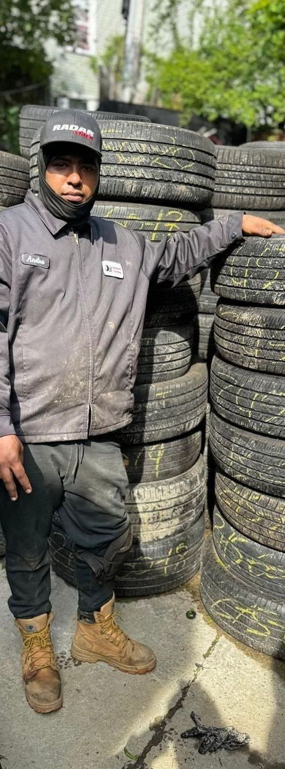 A man is standing in front of a pile of tires.