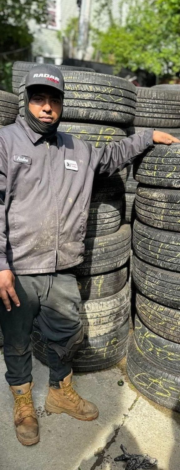 A man is standing in front of a pile of tires.