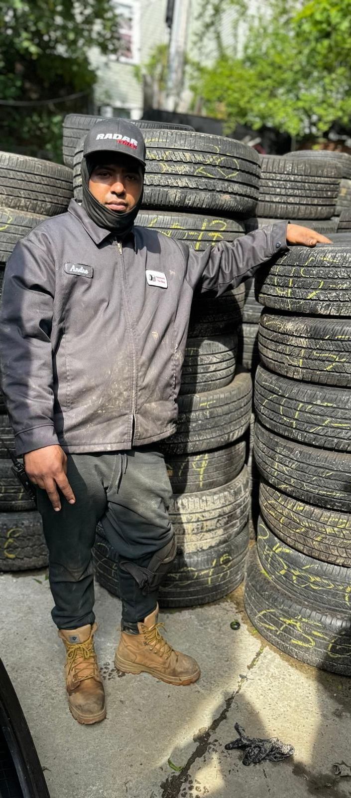 A man is standing in front of a pile of tires.
