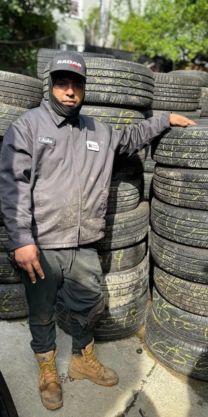 A man is standing in front of a pile of tires.