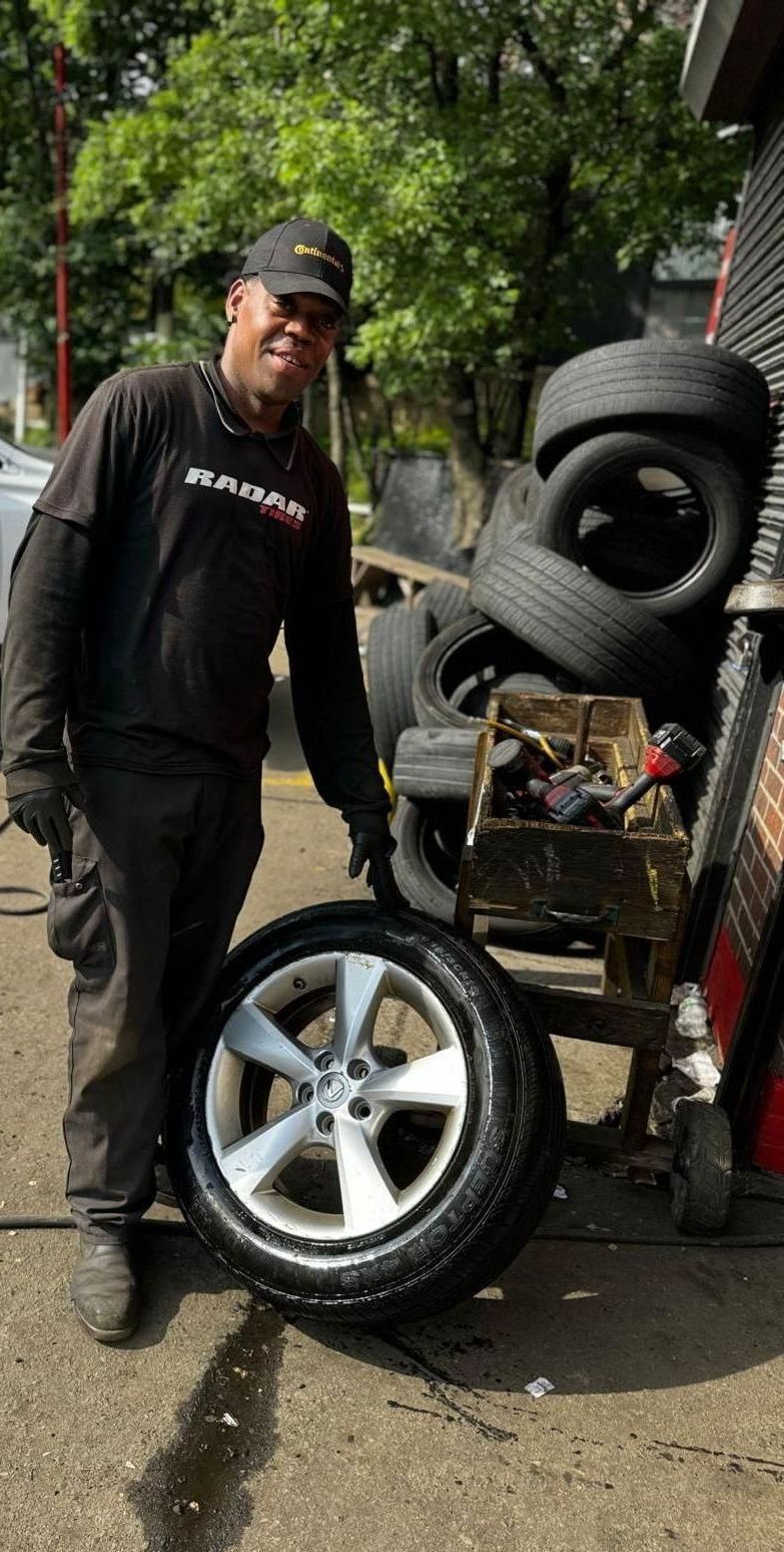 A man is standing next to a tire in front of a pile of tires.