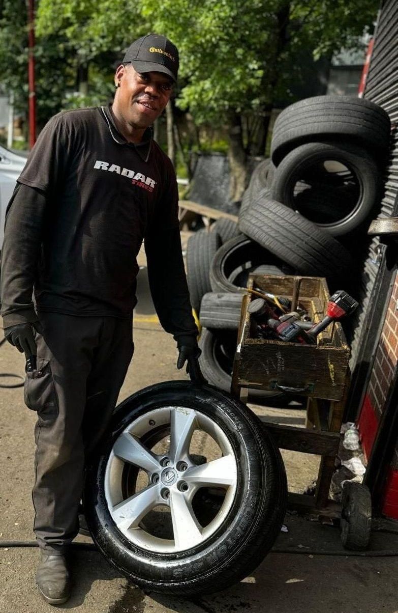 A man is standing next to a tire in front of a pile of tires.
