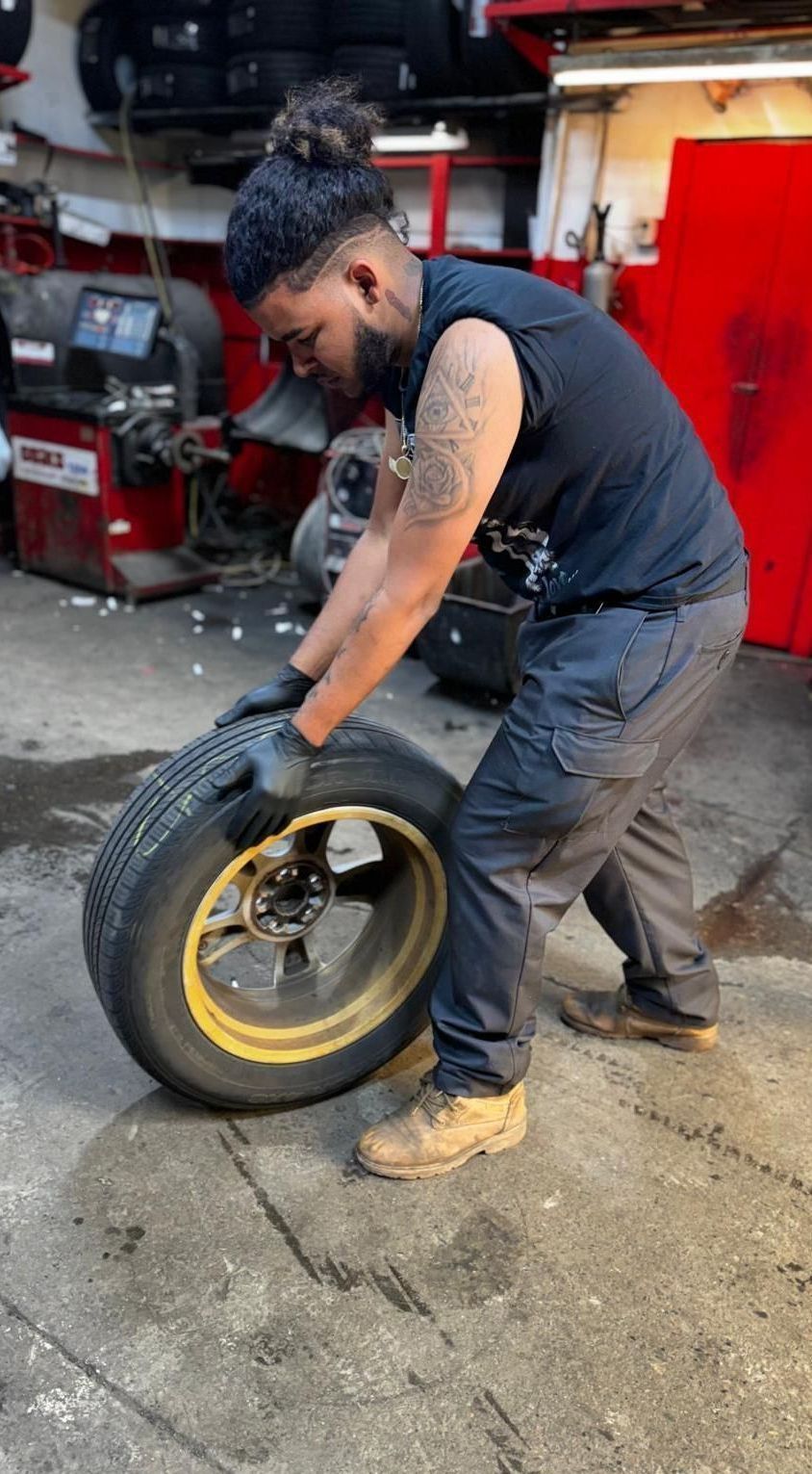 A man is changing a tire in a garage.