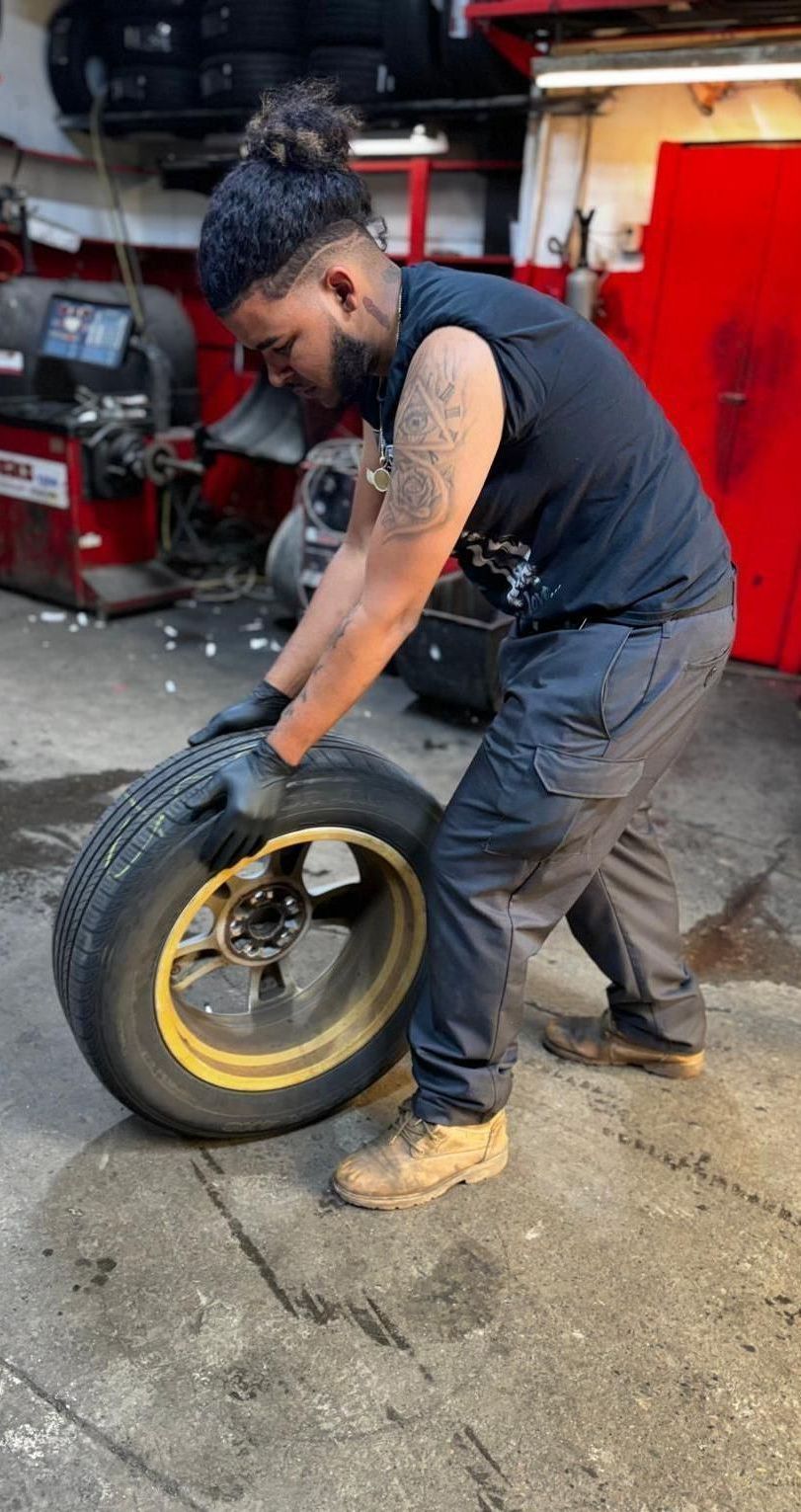 A man is changing a tire in a garage.