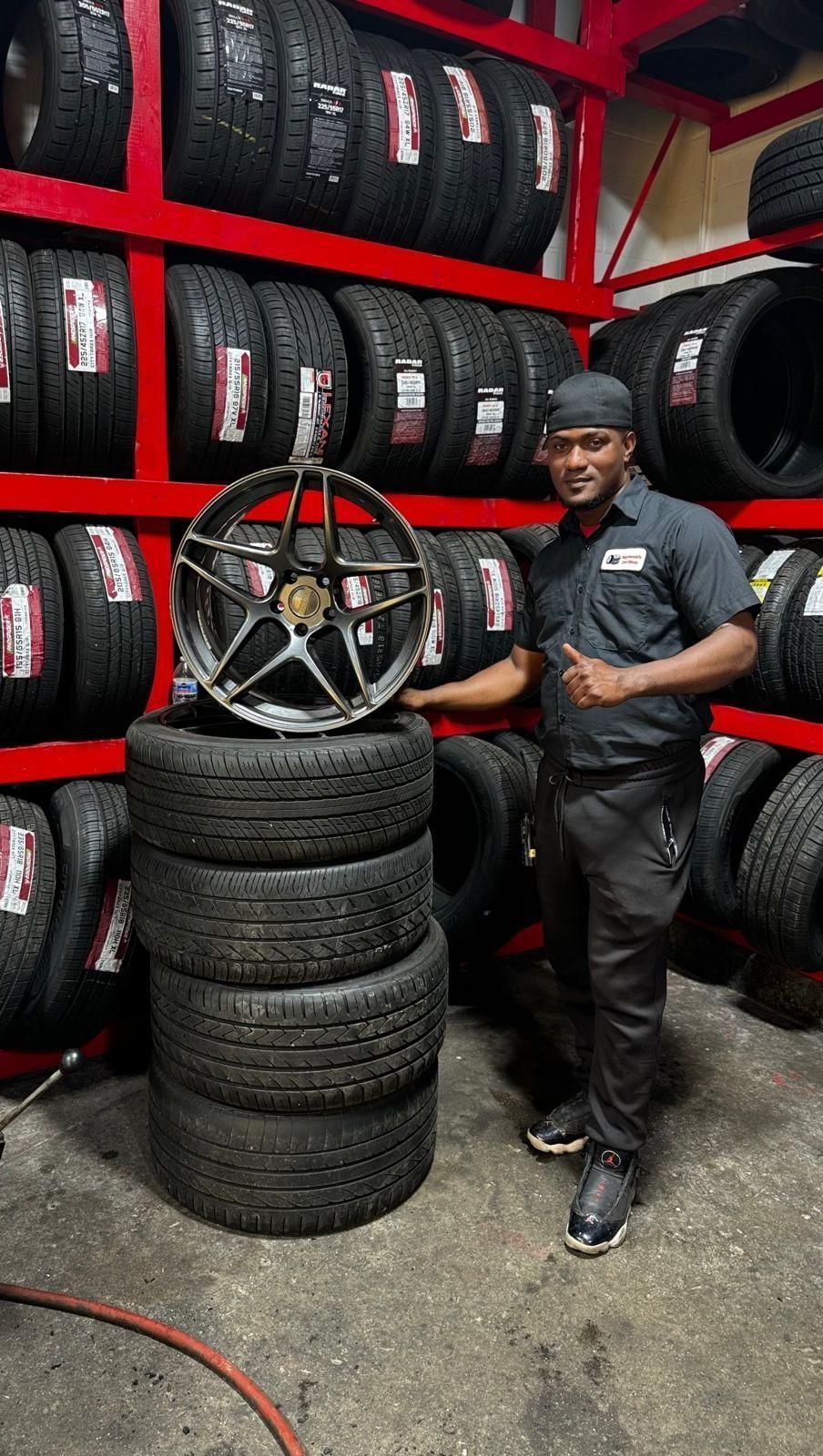 A man is standing next to a pile of tires in a tire store.
