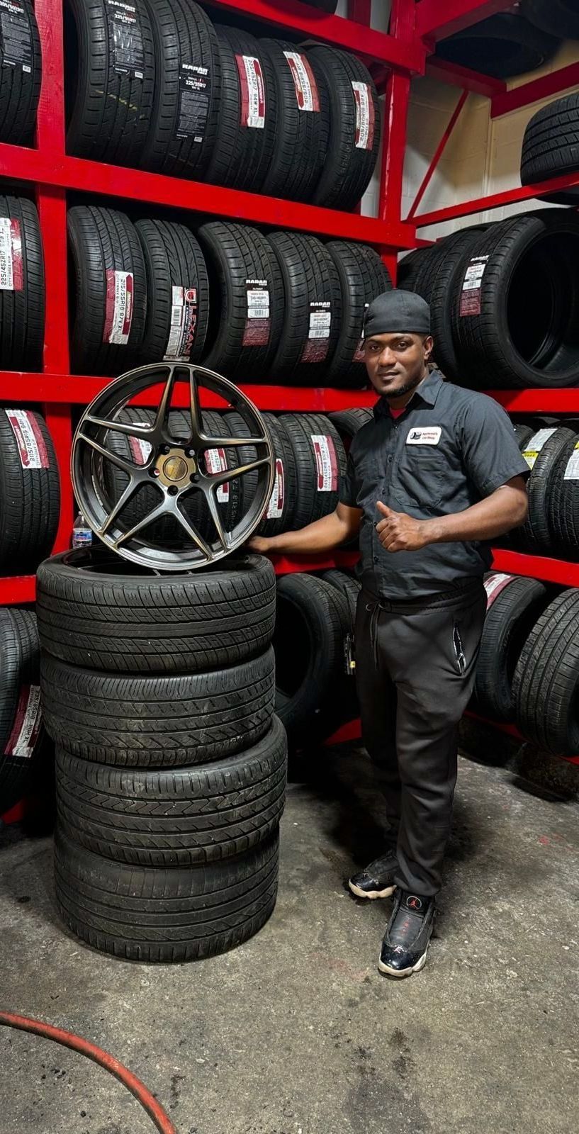A man is standing next to a pile of tires in a tire store.