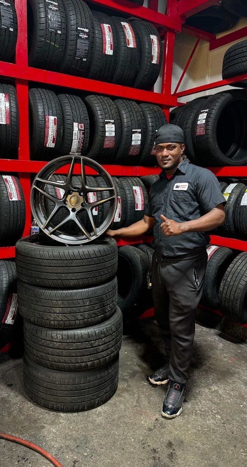 A man is standing next to a pile of tires in a tire store.
