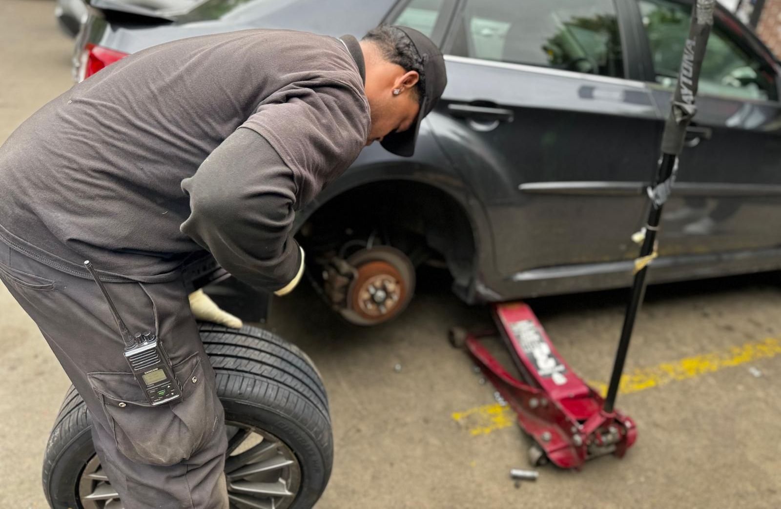 A man is changing a tire on a car in a parking lot