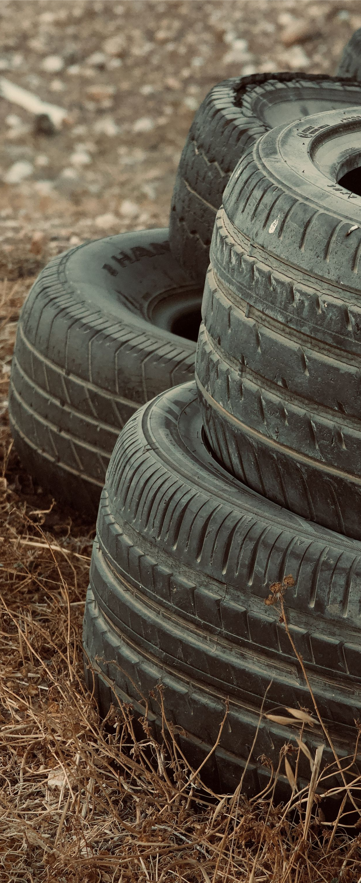 Stack of worn black tires on dirt ground