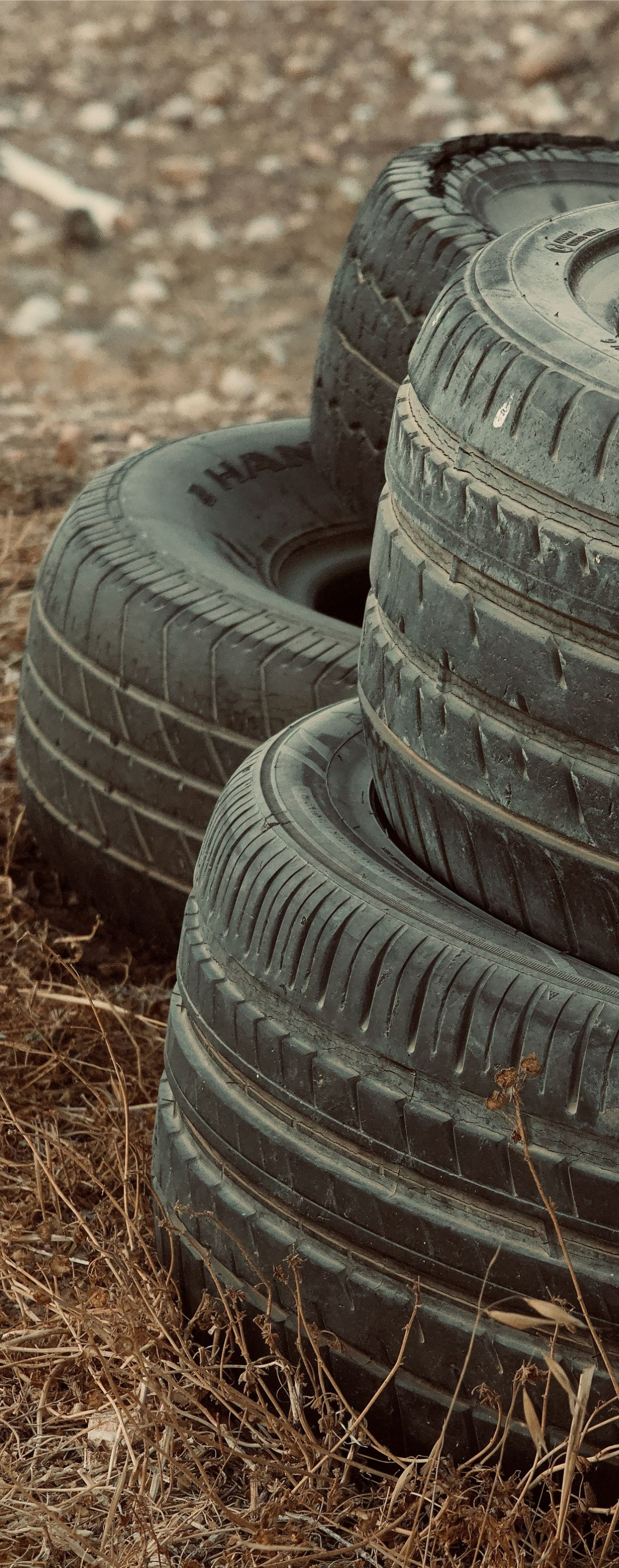Stack of worn black tires on dirt ground