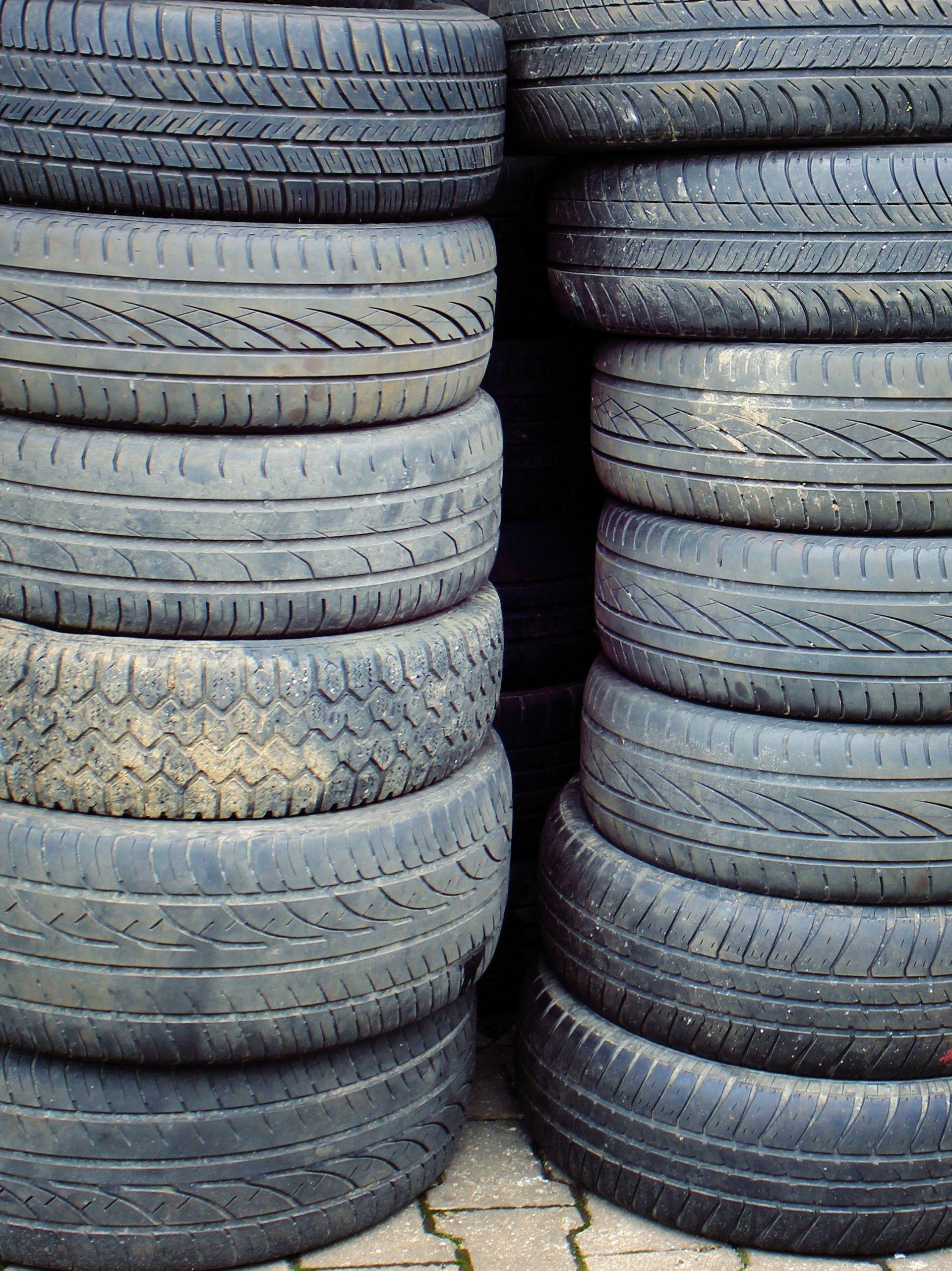 Stacks of used car tires piled in rows outdoors.