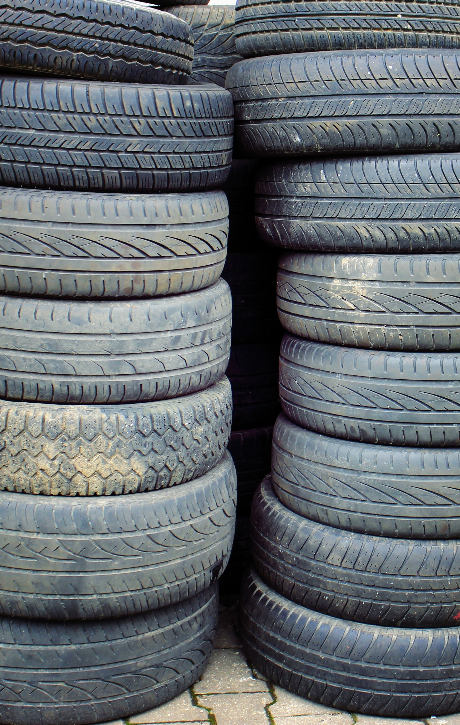 Stacks of used car tires piled in rows outdoors.