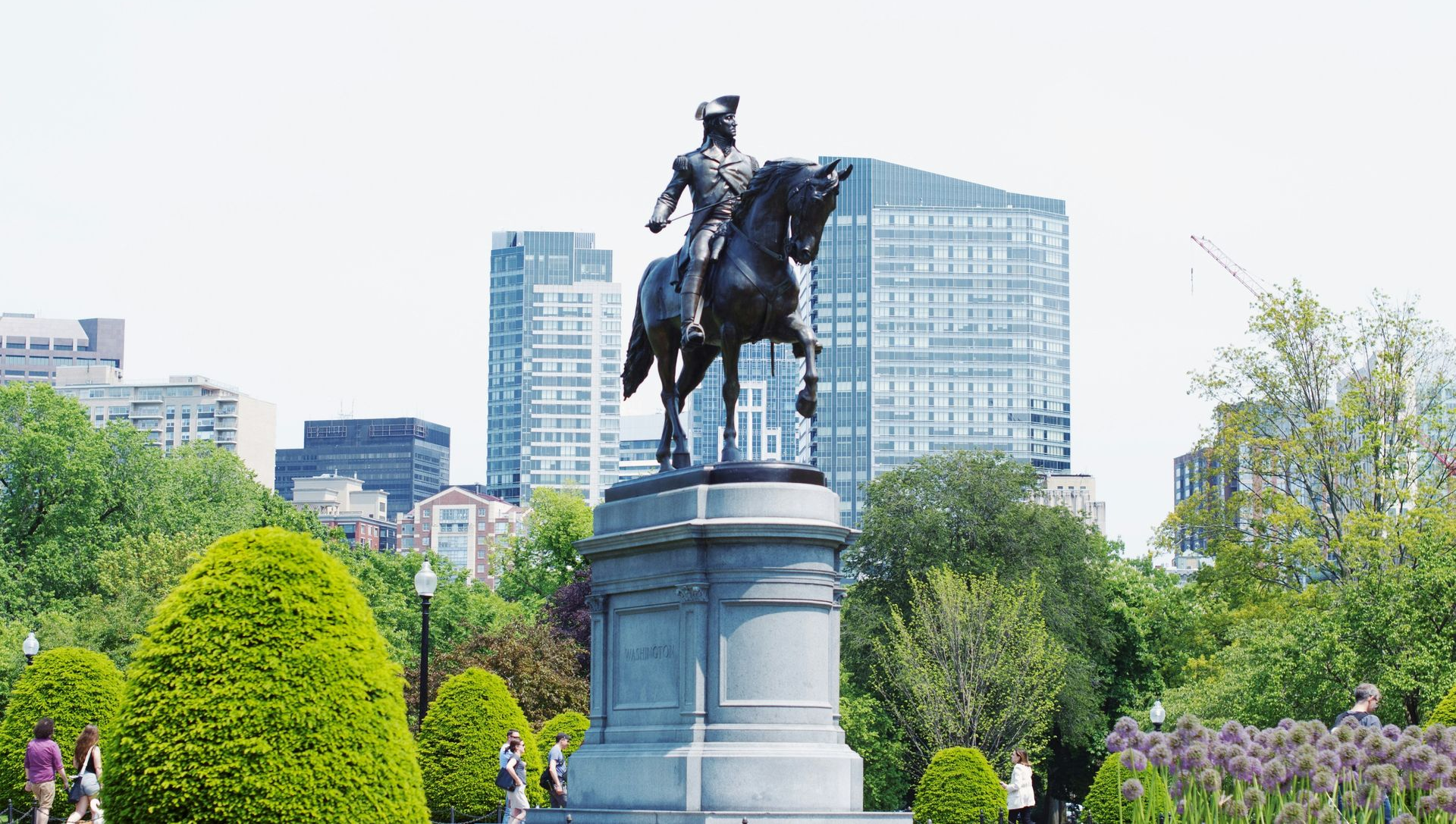 A bronze equestrian statue of George Washington stands on a stone pedestal in the Boston Public Garden.