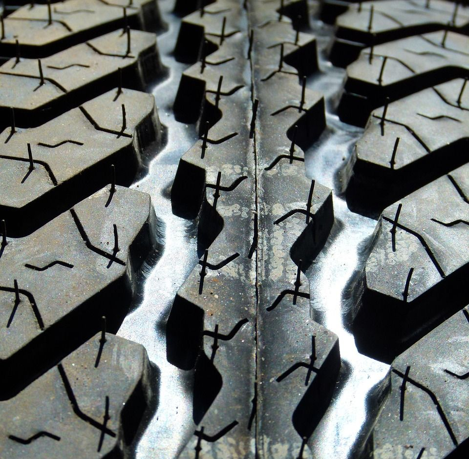 Close-up view of a tire tread with deep, angled grooves and small, textured sipes.