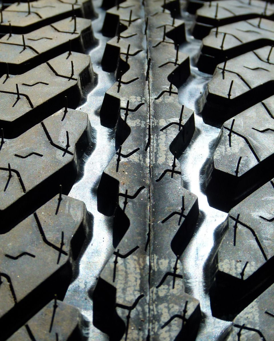 Close-up view of a tire tread with deep, angled grooves and small, textured sipes.