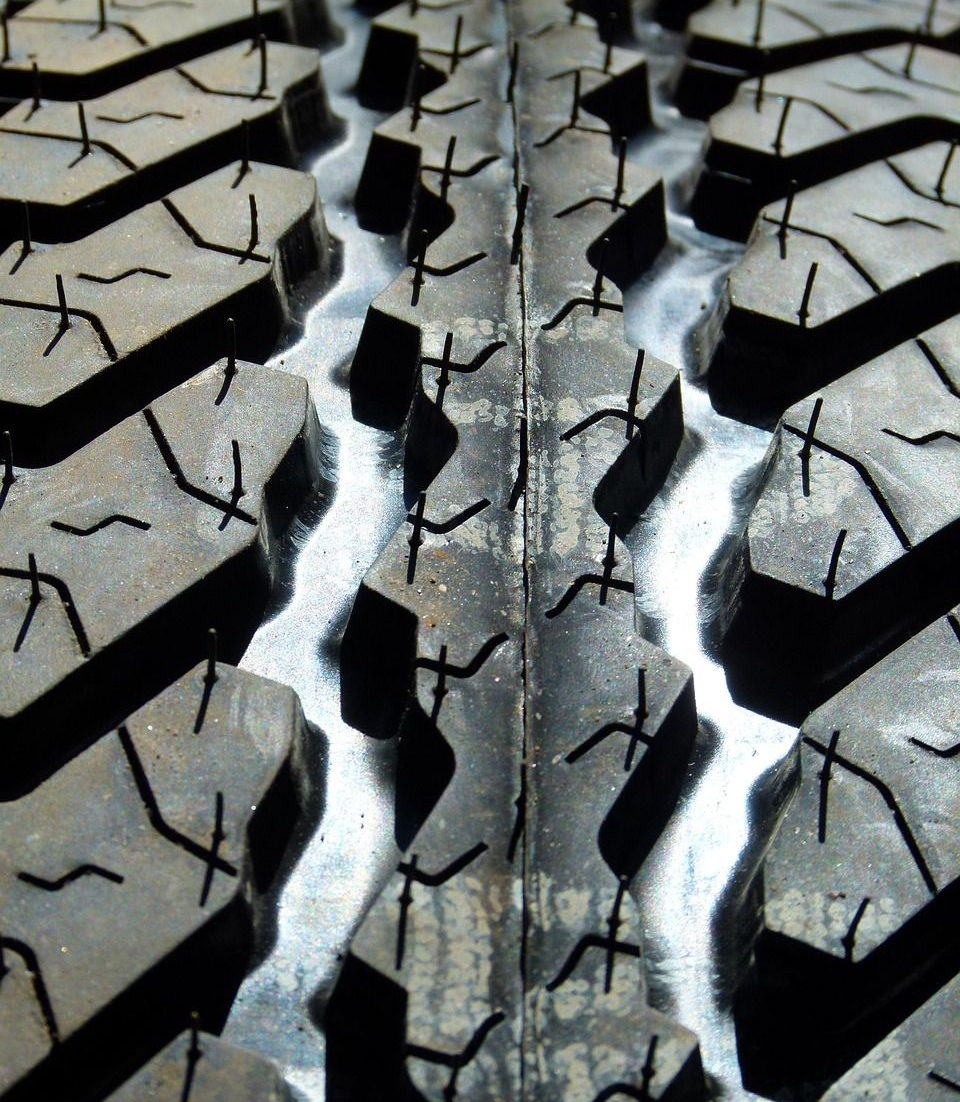 Close-up view of a tire tread with deep, angled grooves and small, textured sipes.
