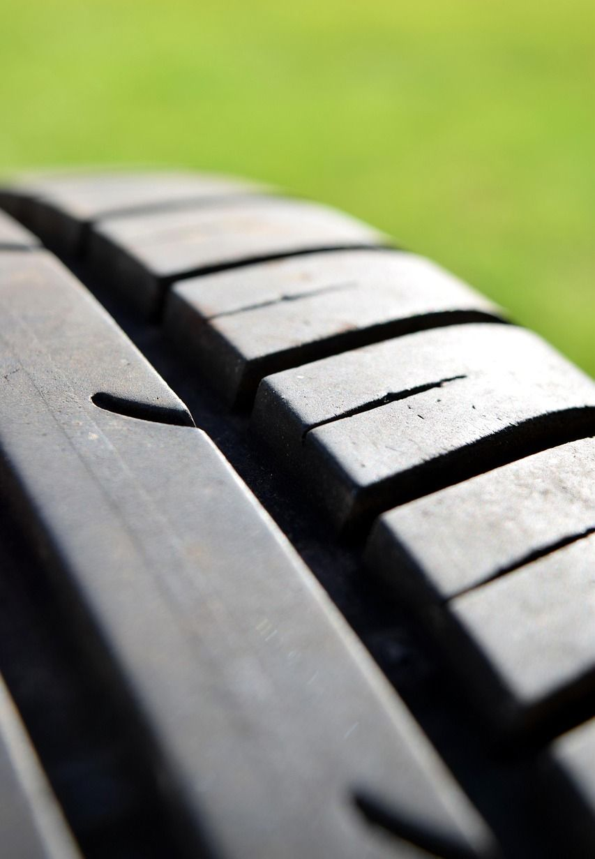 Close-up of a tire tread with grooves against a blurred green background.