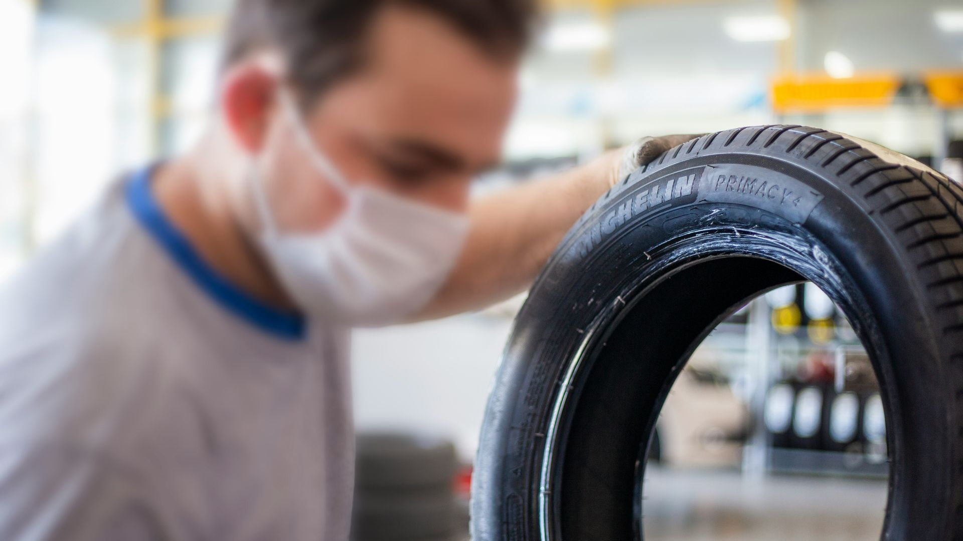 Mechanic wearing a mask inspects a tire in a workshop