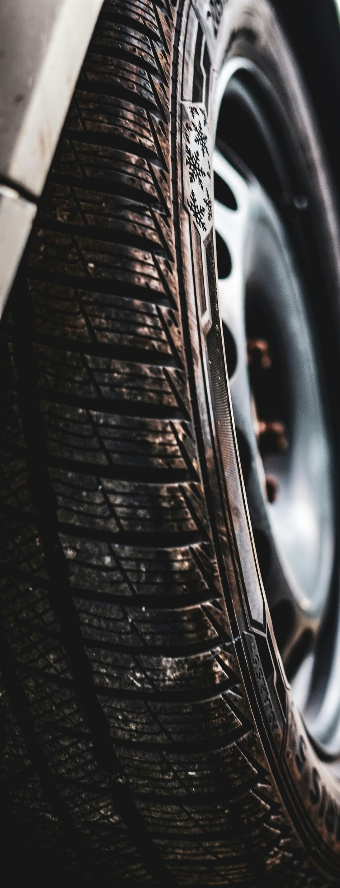 Close-up of a wet car tire with tread and wheel rim visible