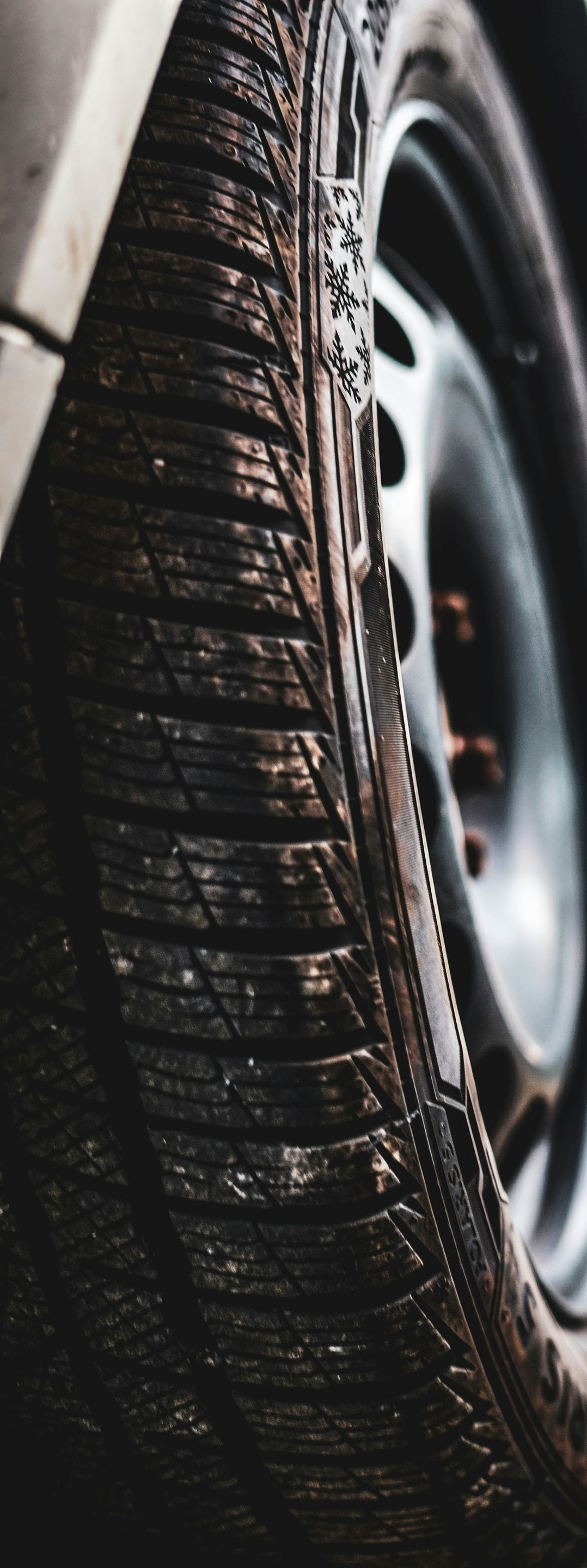 Close-up of a wet car tire with tread and wheel rim visible