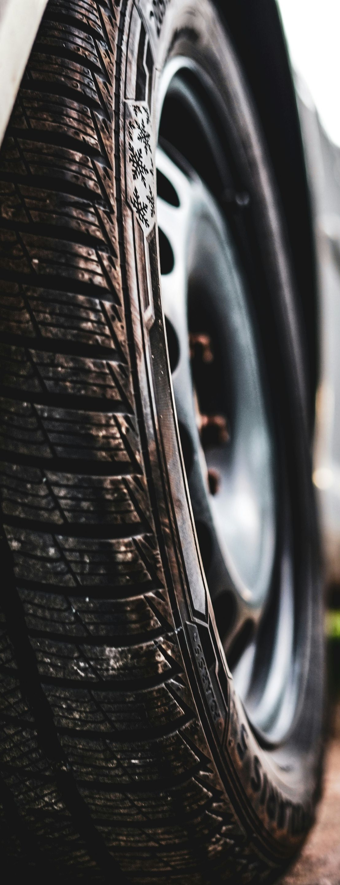 Close-up of a wet car tire with tread and wheel rim visible