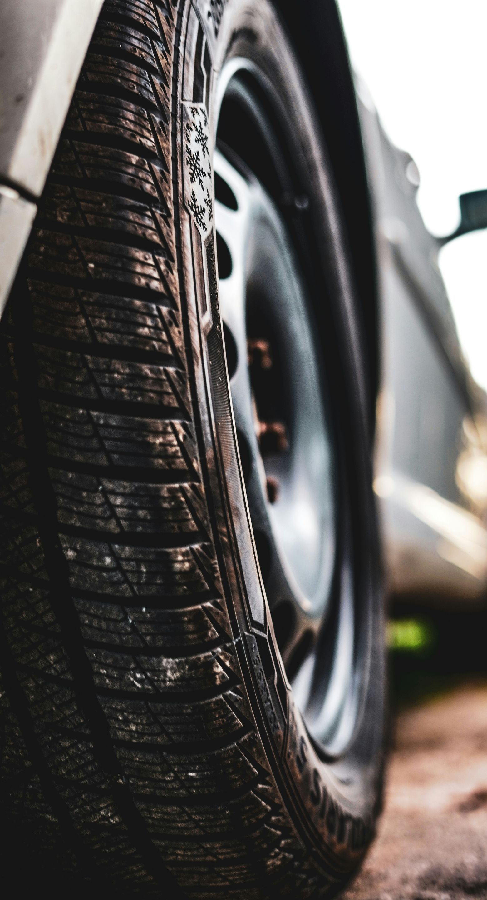 Close-up of a car tire with wet tread beside a black wheel rim.