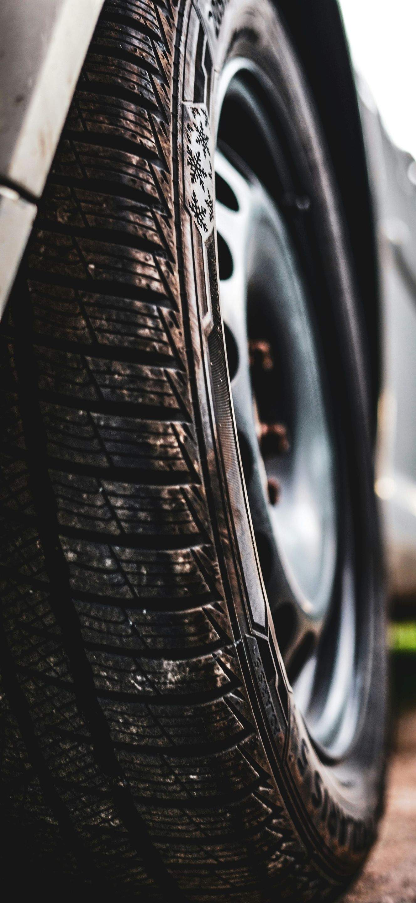 Close-up of a car tire with wet tread beside a black wheel rim.