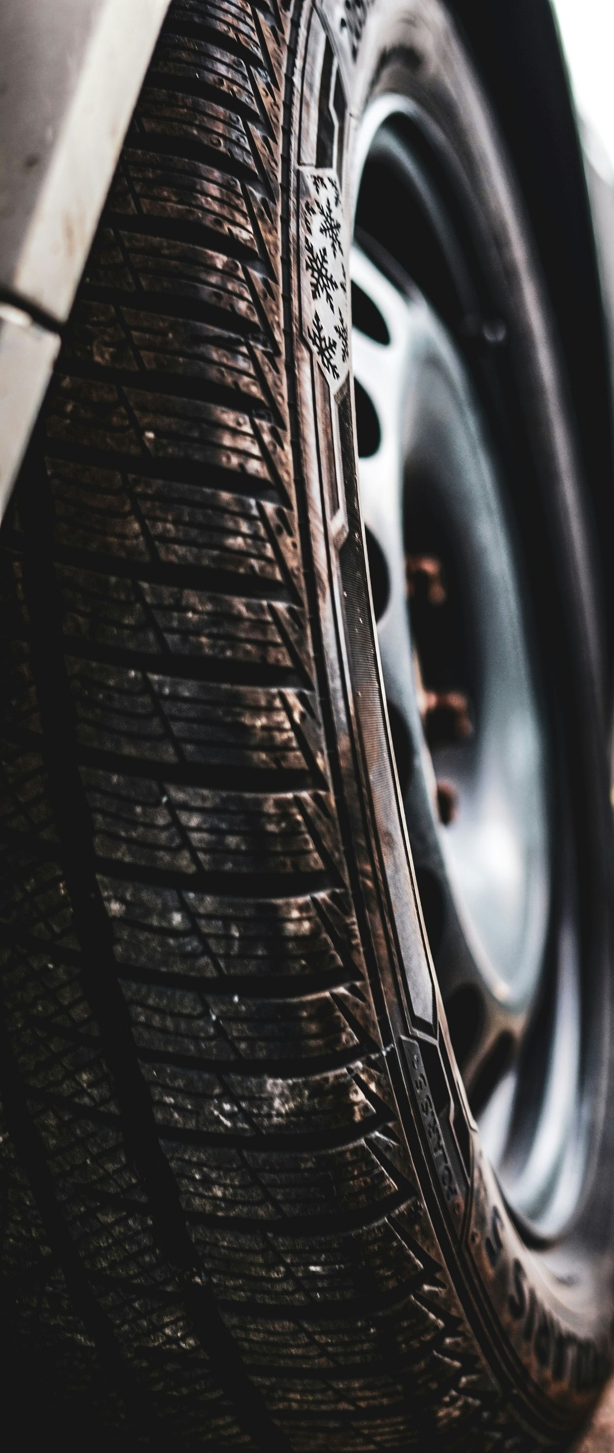 Close-up of a car tire with wet tread beside a black wheel rim.