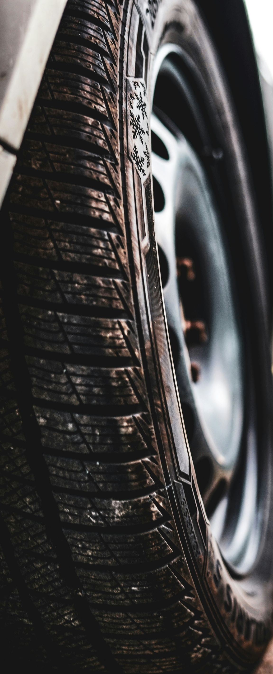 Close-up of a car tire with wet tread beside a black wheel rim.