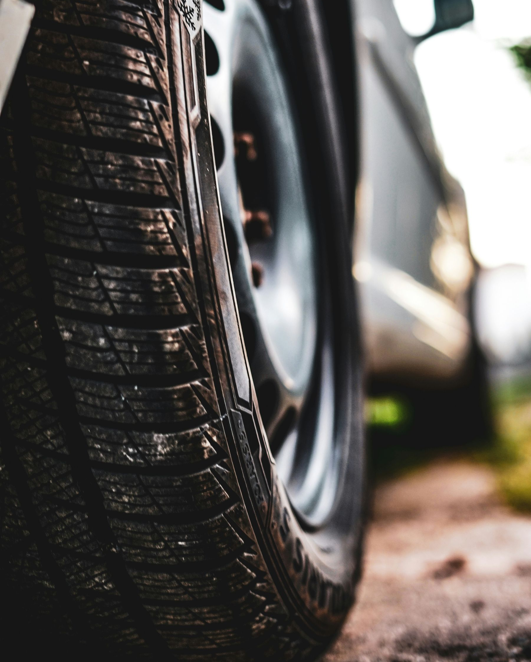 Close-up view of a car tire on a dirt road, captured from a low angle with a shallow depth of field.