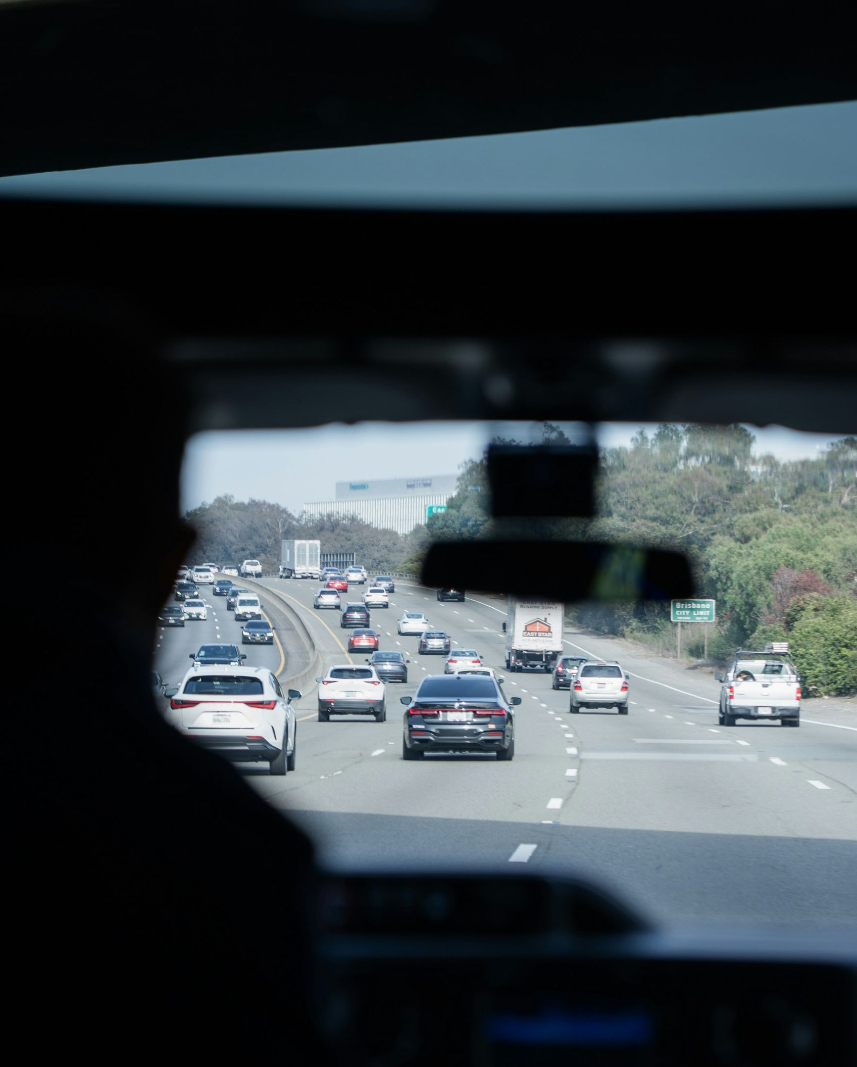 Traffic on a multi-lane highway seen through a car’s rearview mirror at dusk