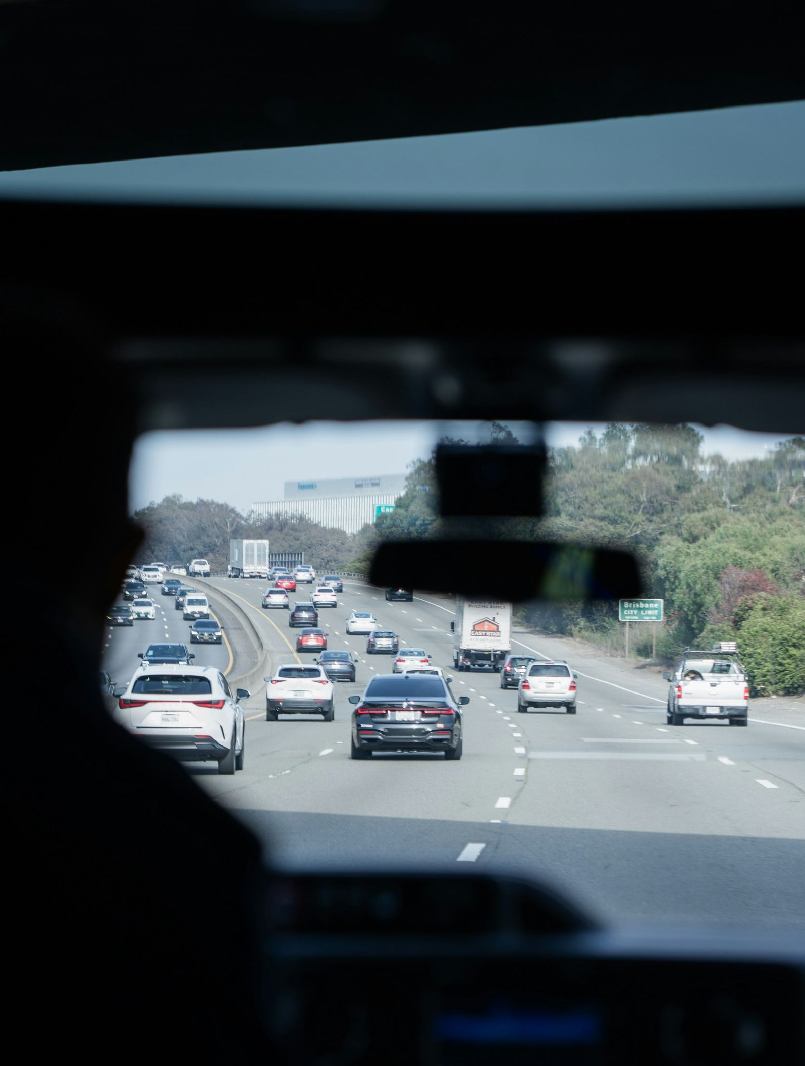 Traffic on a multi-lane highway seen through a car’s rearview mirror at dusk