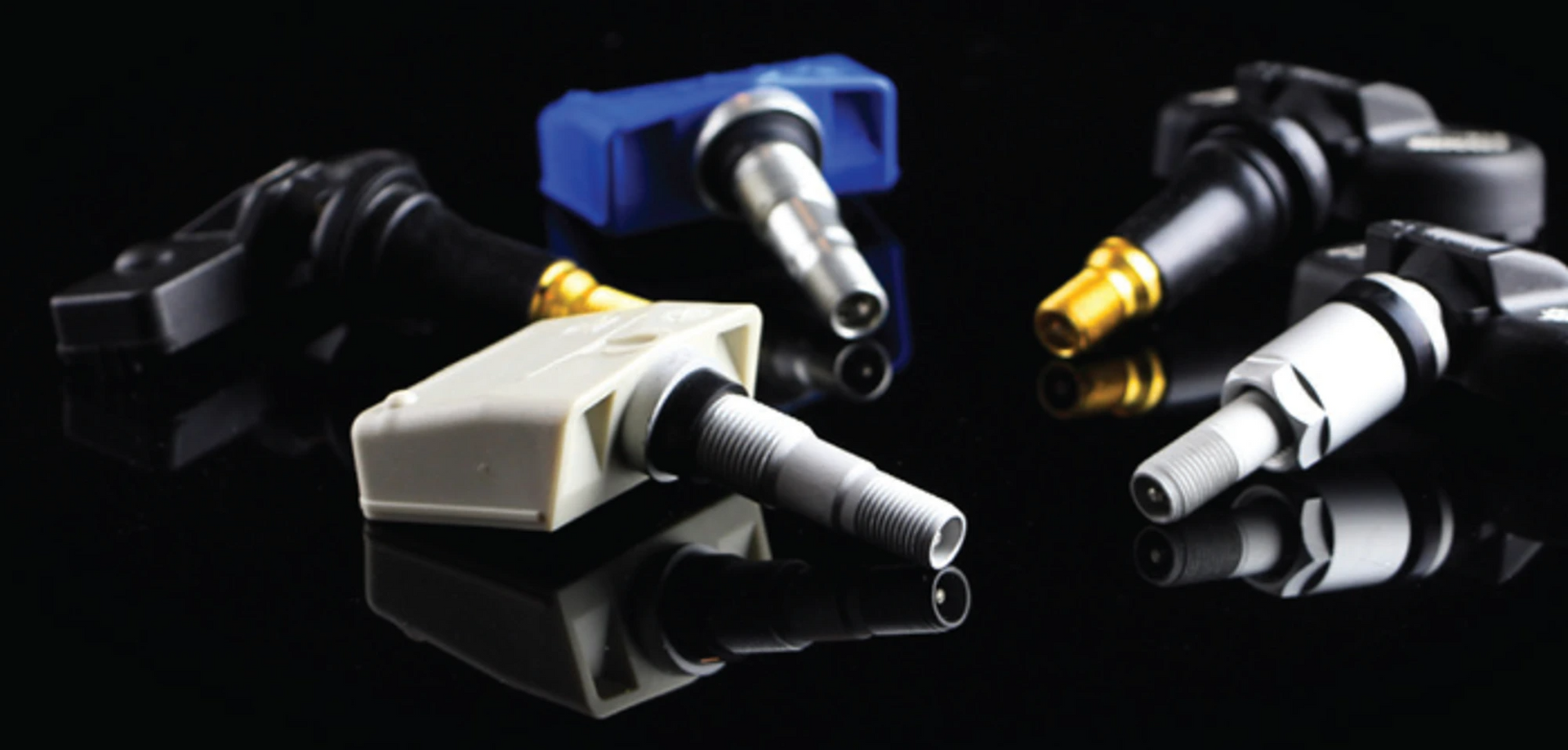 Assorted metallic flash drive connectors on a black reflective surface, with blue, silver, and gold accents