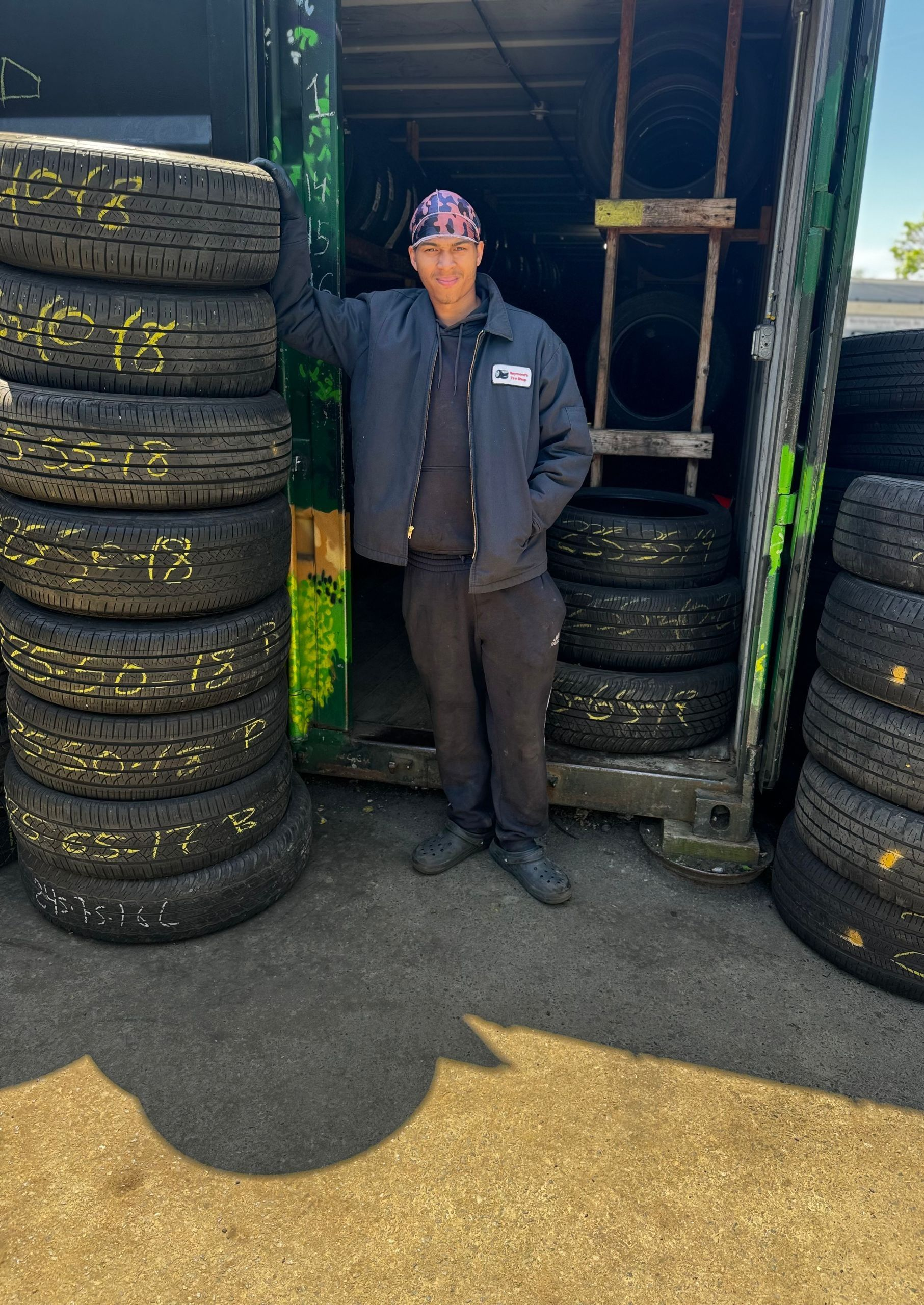 Person standing between stacks of tires outside a garage doorway