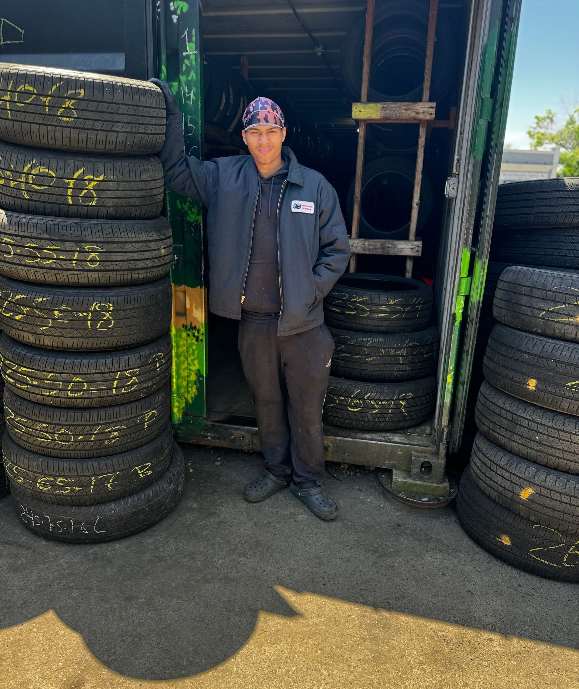 Person standing between stacks of tires outside a garage doorway