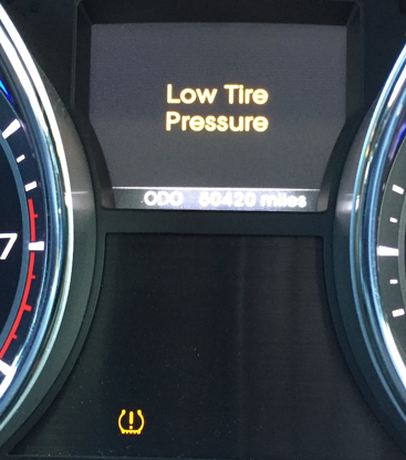 Car dashboard warning light and display reading “Low Tire Pressure” in yellow.