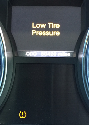 Car dashboard warning light and display reading “Low Tire Pressure” in yellow.